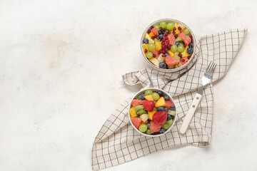 Fototapeta na wymiar Bowls of fresh fruit salad on light background