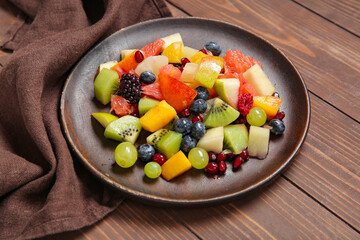 Plate of fresh fruit salad on wooden background