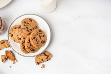 Plate of tasty cookies with chocolate chips on white background