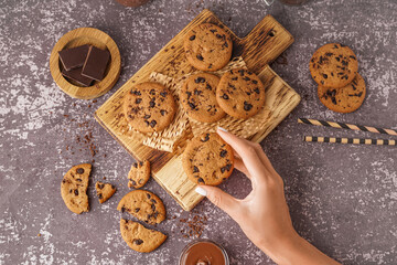 Woman eating tasty cookies with chocolate chips on grey background