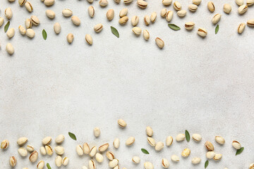 Fototapeta na wymiar Tasty pistachio nuts and leaves on white background