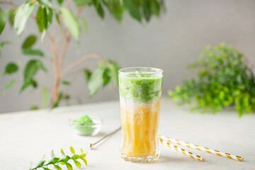 Iced mango matcha latte in glass on the table