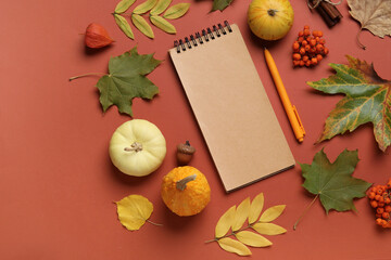 Composition with blank notebook, pen, pumpkins and autumn leaves on color background