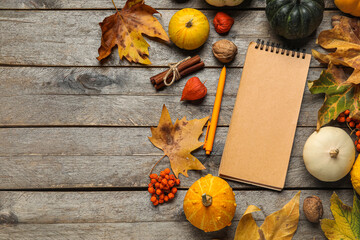 Composition with notebook, pumpkins and autumn leaves on brown wooden background