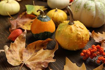 Composition with pumpkins and autumn leaves on brown wooden background