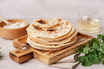 Wooden board of tasty pita bread on white background