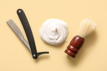 Shaving foam with razor and brush on beige background
