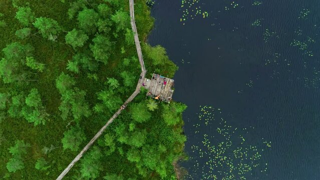 Rising overhead aerial shot of a wooden walkway lining Lake Lubans.