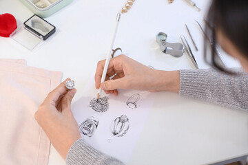 Female jewelry designer drawing sketch for stylish accessory at workplace