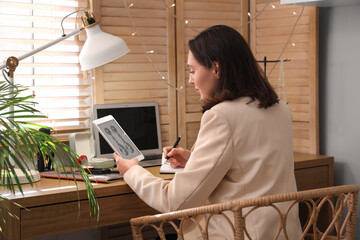 Female jewelry designer working with laptop in office