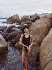 Summer Sensuality: A Beautiful Woman in Sexy Swimwear Poses on a Rock, Enjoying the Beach and Ocean