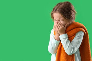 Sick little girl in scarf on green background