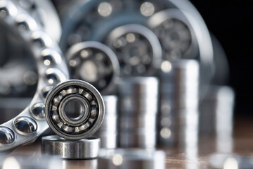 Metal radial ball bearings for mechanical engineering, machine tools and large equipment in the form of a diagram rising up on a blurred glare background of metal products in macro with copy space.