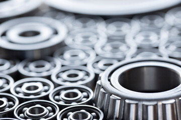 Surface laid with steel ball radial bearings for large machinery, equipment and mechanical engineering close-up. Bearings close-up in gray silver shades with blurred background. - obrazy, fototapety, plakaty
