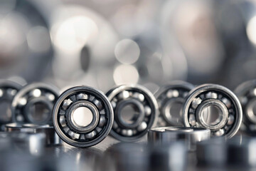 Radial ball bearings close-up in silver color for mechanical engineering, machine tools and equipment. Round steel bearings with balls at the base with a blurred glare background. - obrazy, fototapety, plakaty