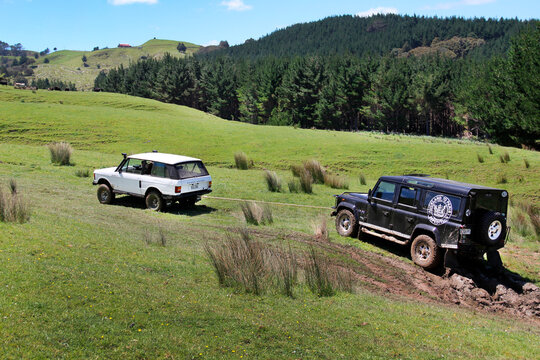 Range Rover Classic 2-door 1978 towing Land Rover Defender 110 TD5 County 2001 from mud. Defender has Auckland to Paris Expedition logo. In Auckland Region, New Zealand on November 10, 2012.