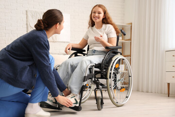 Fototapeta na wymiar Young redhead woman in wheelchair with nurse at home