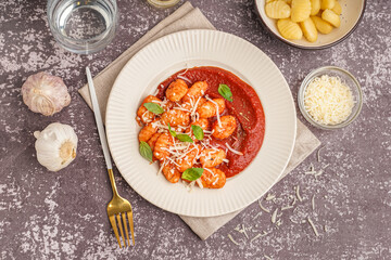 Plate of tasty gnocchi with tomato sauce and cheese on grey background