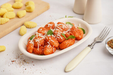 Plate of tasty gnocchi with tomato sauce and cheese on white background