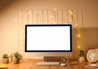Workplace with blank computer monitor, pin board and glowing lights in office at night