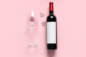 Bottle of wine with glass and hearts on pink background. Valentine's Day celebration
