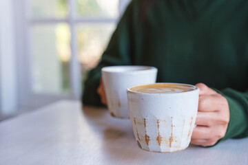 Closeup image of a woman holding and serving two cups of hot coffee