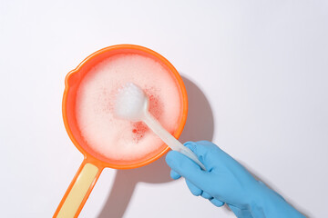 Hand wearing rubber gloves holding a toilet brush dipped in a plastic bucket filled with soap solution on a white background. Cleaning concept. © Tuan  Nguyen 