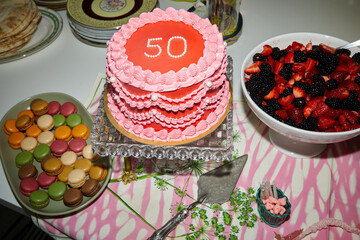 Pink and red 50th birthday cake and dessert spread