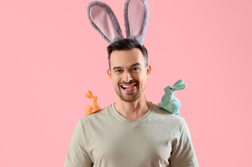 Happy young man in bunny ears with Easter rabbits on pink background