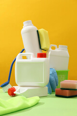 Colorful cleaning products on a plain yellow background. White bottle and canisters mockup for...