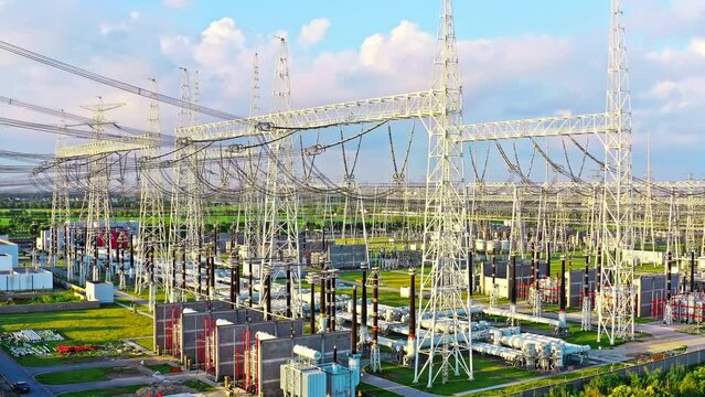 Aerial video of high voltage transmission towers in substation scenery at sunset. Drone surround shooting.