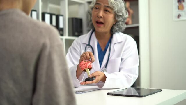 Female doctor explaining to patient results of model  brain. Diagnosis of diseases and head injuries.