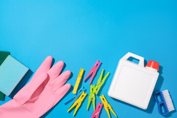 A sponge, a pink rubber glove, colorful clothespins, a white detergent bottle and a brush are...