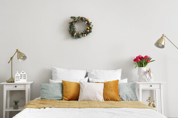 Interior of light bedroom with Easter wreath and tables