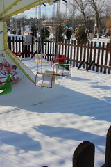 children's swing in the snow in winter in the park