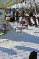 children's swing in the snow in winter in the park