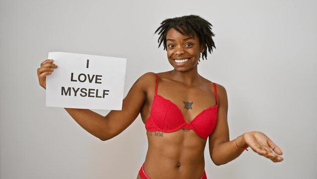 Triumphant young black woman with dreadlocks celebrating self-love, declaring 'i love my body' with a winner's grin. exuding joy and confidence against a pure white backdrop.