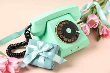 Retro telephone with gift box and beautiful tulips on pink background. International Women's Day