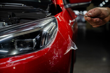 The process of applying protective vinyl film to car headlights in detailing. 