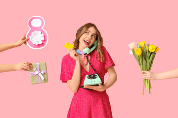 Young woman talking by retro telephone with credit card and hands holding gift box with figure 8 made of paper on pink background. International Women's Day