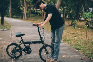 Young handsome bearded man taking a break while travelling the city with his bicycle using his digital tablet looking away thoughtfully