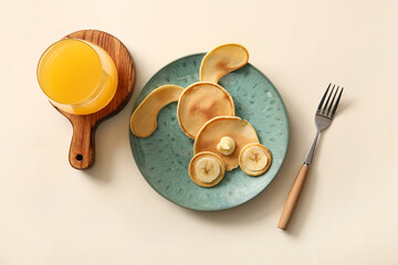 Funny Easter bunny pancakes with glass of orange juice on beige background