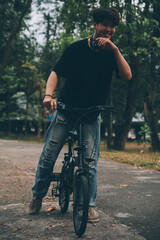 Young handsome bearded man taking a break while travelling the city with his bicycle using his digital tablet looking away thoughtfully