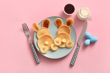 Funny Easter bunny pancakes with banana and painted eggs on pink background
