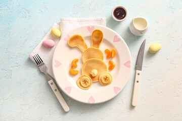 Funny Easter bunny pancakes with banana and painted eggs on light blue background