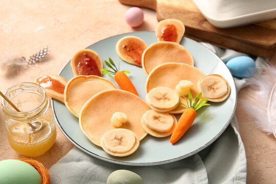 Funny Easter bunny pancakes with carrot and banana on beige background