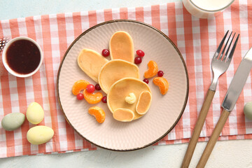 Funny Easter bunny pancakes with mandarin and berries on light blue background