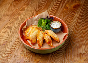 Mini pasties with meat in a plate on a wooden background