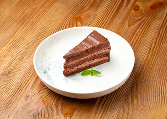 Piece of chocolate cake on a plate on a wooden background