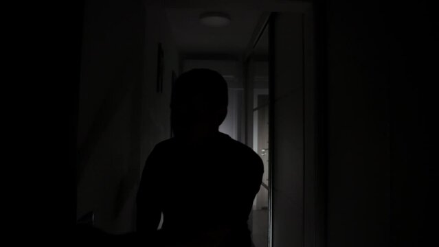 An Anxious Man is Searching for a Hiding Spot in the Dark House - Pullback Shot